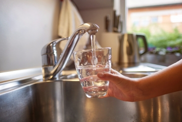 child holding glass under faucet