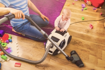 dad vacuuming next to baby