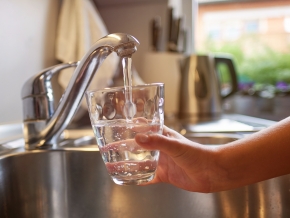 child with glass under faucet